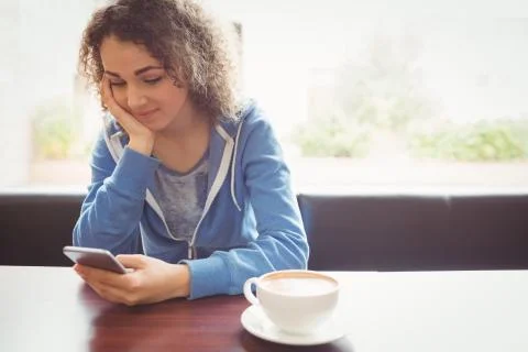 Pretty student using her phone in cafe 写真素材