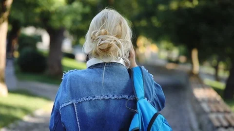Pretty student wanders along park and talks on smartphone Stock Footage 113672561