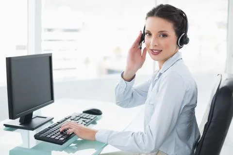 Pretty stylish brunette operator using a computer and answering a call Stock Photos