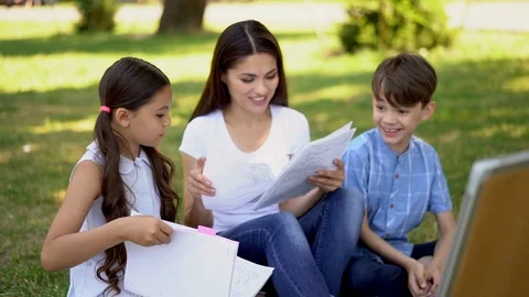 Pretty teacher with two young students laughing during outdoors lesson Stock Footage 126732071