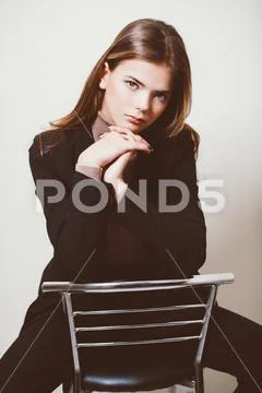 A pretty teenage girl is sitting on a bar stool. Beauty, fashion. Stock Photos