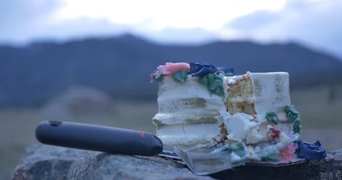 Pretty wedding cake with a slice cut out plated on top of a boulder in the Video stock 113691826