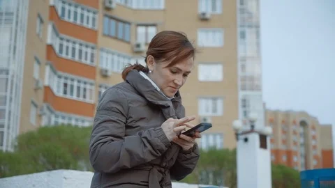 A pretty woman on a bench in the background of a multi-storey house flips Stock Footage 77501933