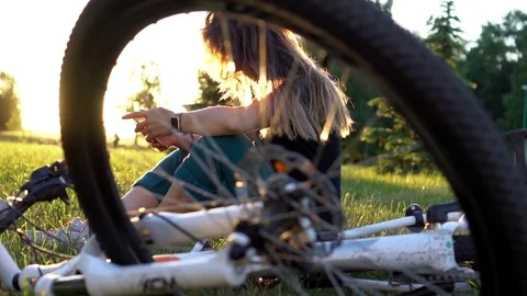 Pretty woman browses web using app on smartphone in city park at sunset. Bike Stock Footage 78306196