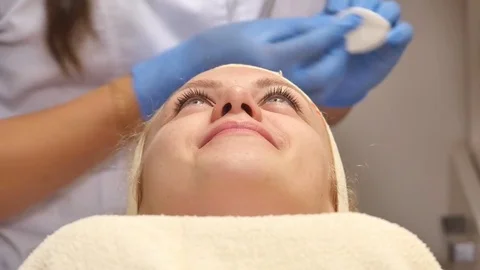 A pretty woman with closed eyes, lying on the cosmetologists table, the Stock Footage