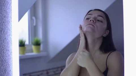 Pretty woman doing makeup in front of mirror in bathroom Stock Footage 69918063