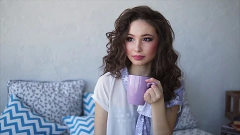 Pretty woman dressed in pajamas drinks morning coffee in her bedroom. Stock Footage