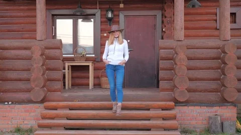 Pretty Woman In The Hat Comes Down The Steps Of The Veranda Of A Wooden House Stock Footage 83209938