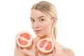 The pretty woman holding two halves of a grapefruit on the white background Photo