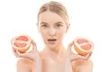 The pretty woman holding two halves of a grapefruit on the white background Photo