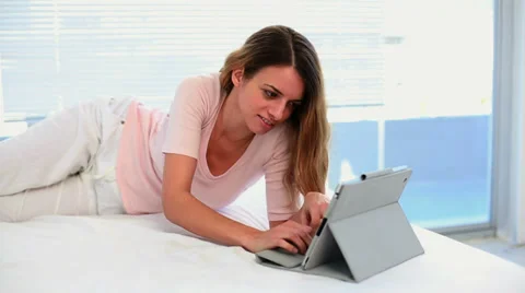 Pretty woman lying and using her tablet pc Stock Footage 29399145