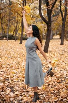 Pretty woman posing with maple's leaf in autumn park near big tree. Beautiful Stock Photos