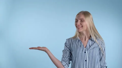 Pretty woman presenting something on empty hand with blue background Video stock 155807738