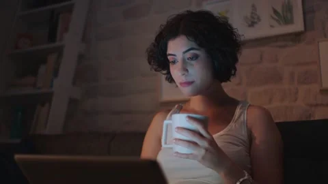 Pretty woman is reading a message on the computer while sitting at her home. Stock Footage 140871768