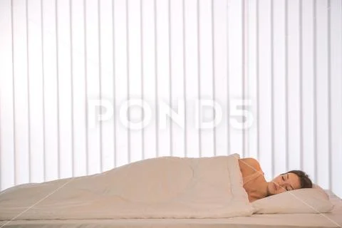 The pretty woman sleeping in the bed with a white linens Stock Photos