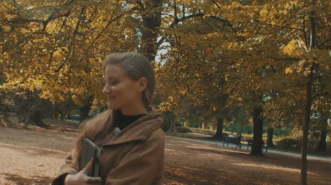 Pretty woman with tablet computer walking in the autumnal park. Stockbeeldmateriaal 55535738