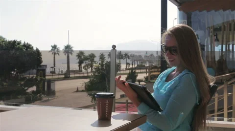 Pretty woman use a tablet computer drink coffee sitting in a cafe in the summer Stock Footage 68814558