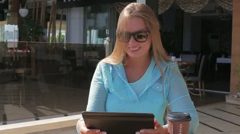 Pretty woman use a tablet computer drink coffee sitting in a cafe in the summer Stock Footage 68816055