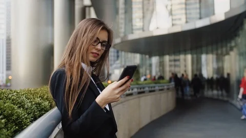 Pretty woman using app on smartphone and texting message in the office centre Stock Footage 101085234