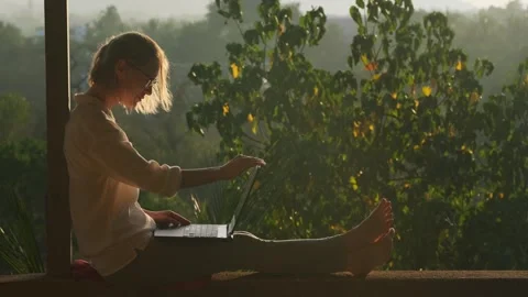 Pretty woman using laptop while sitting on the rooftop in sunlight. Stock Footage 246598193