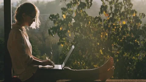 Pretty woman using laptop while sitting on the rooftop in sunlight. Stock Footage 262022050