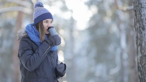 Pretty woman in winter hat enjoys the snow and drinks hot beverage Stock Footage 59607126