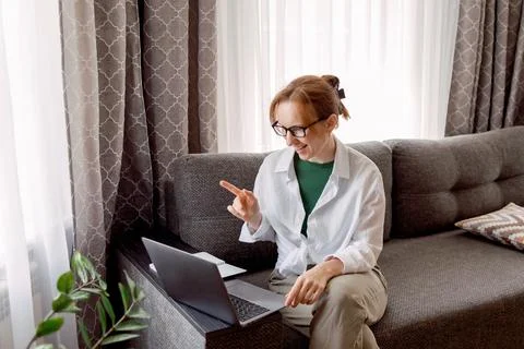 Pretty womanusing laptop elearning or remote working at home office looking at Stock Photos