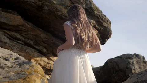 Pretty young bride on the rocks in the sunset Stock Footage 129072978
