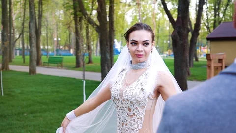 Pretty young bride walking around the groom in sunny park Stock Footage 107134886