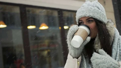 Pretty young brunette drinking coffee outside on winter Stock Footage 69920678