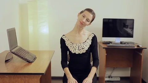 Pretty young female office worker with a long neck stretching and smiling Stock Footage 79917993