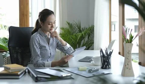 Pretty young female office worker using computer tablet at modern workplace.. Stock Photos
