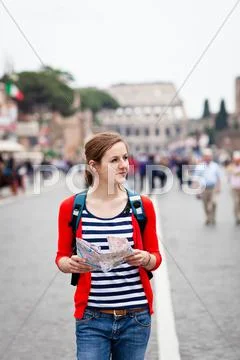 Pretty young female tourist holding a map while walking along th Stock Photos