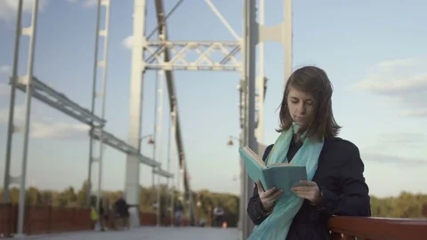 Pretty young girl read book on the bridge Stock Footage