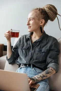 Pretty young girl with using laptop computer drinking tea. Stock Photos