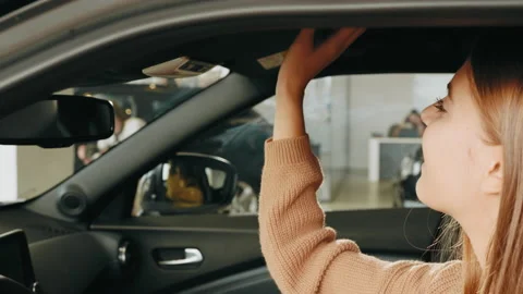 Pretty young lady examining interior of luxury car while sitting inside Stock Footage 176377626