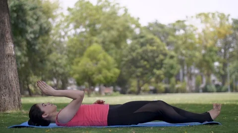 Pretty young lady practicing yoga on green grass with fitness mat in a park Stock Footage 113849941