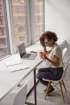 Pretty young lady resting while holding cup of drink in the office Foto stock