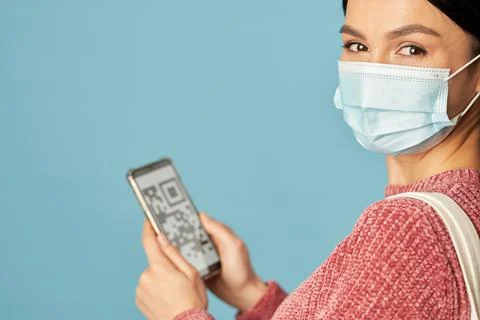 Pretty young lady using smartphone and wearing disposable medical mask Foto stock