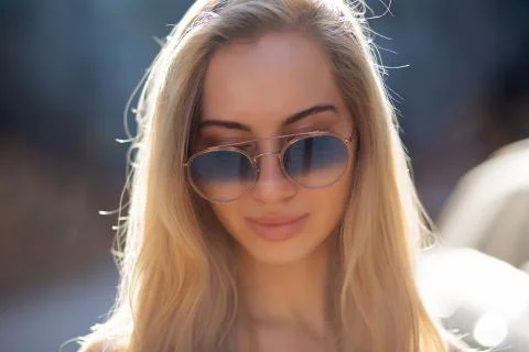 Pretty young model with long hair wearing glasses, posing at the street in su Stock Photos