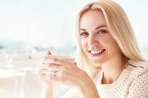 Pretty young woman with cup of coffee in sunny restaraunt Stock Photos