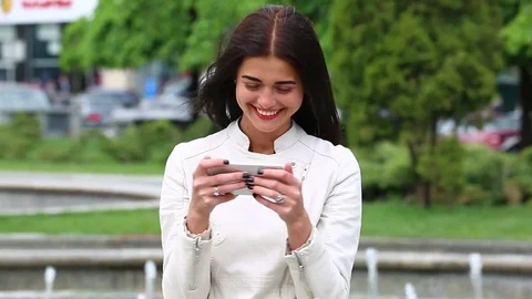Pretty young woman with her mobile phone on fountain background. Video stock 75581853