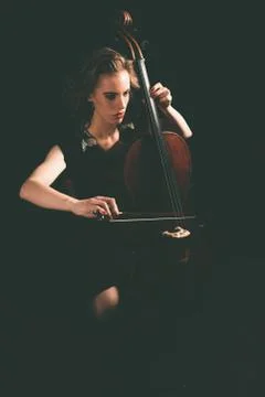 Pretty young woman playing a cello at night Stock Photos
