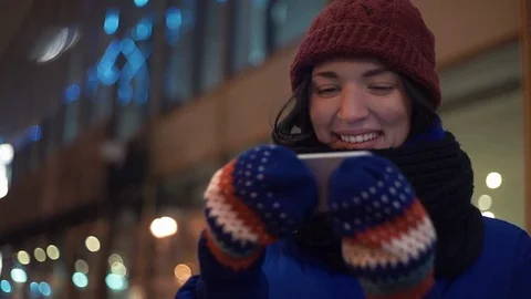 Pretty young woman smiling using a smartphone watching video standing outdoors Stock Footage 83070026