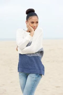 Pretty young woman standing on beach alone in sweater and jeans Foto stock