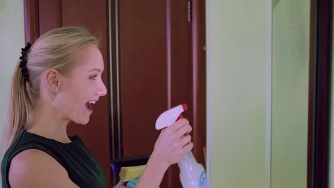 Pretty young woman standing in front of mirror and wiping it Stock Footage