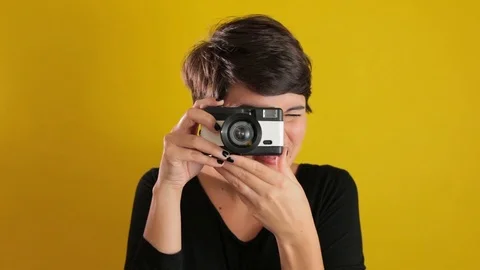 Pretty Young Woman using Camera On solid Yellow Background Stock Footage 95210399