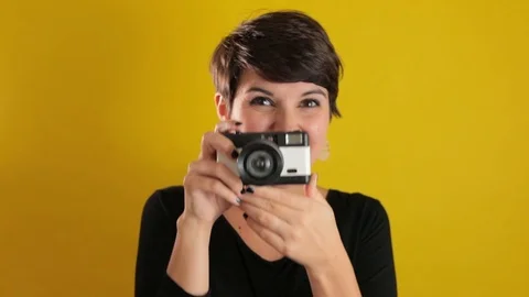 Pretty Young Woman Using Camera On Solid Yellow Background Video stock 95210421
