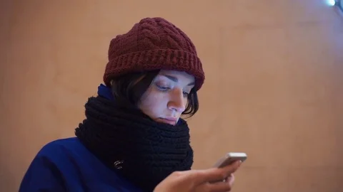 Pretty young woman using cell phone checking mails. Festive lighting on building Stock Footage 83069900