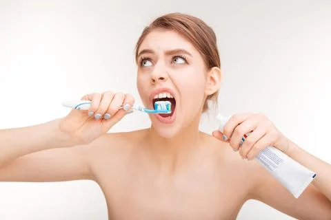 Pretty young woman using toothpaste and brushing her teeth Stock Photos